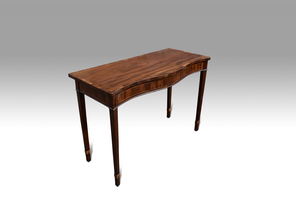 A George III mahogany serpentine console table featuring decorative inlay along the apron and four square tapered legs. View VII