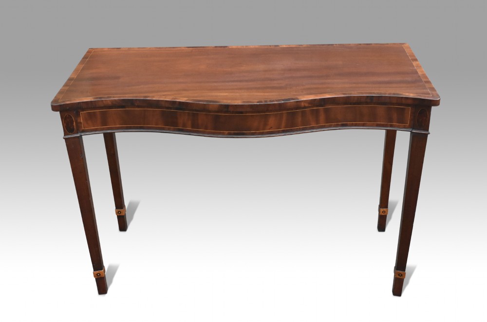 A George III mahogany serpentine console table featuring decorative inlay along the apron and four square tapered legs. View VI