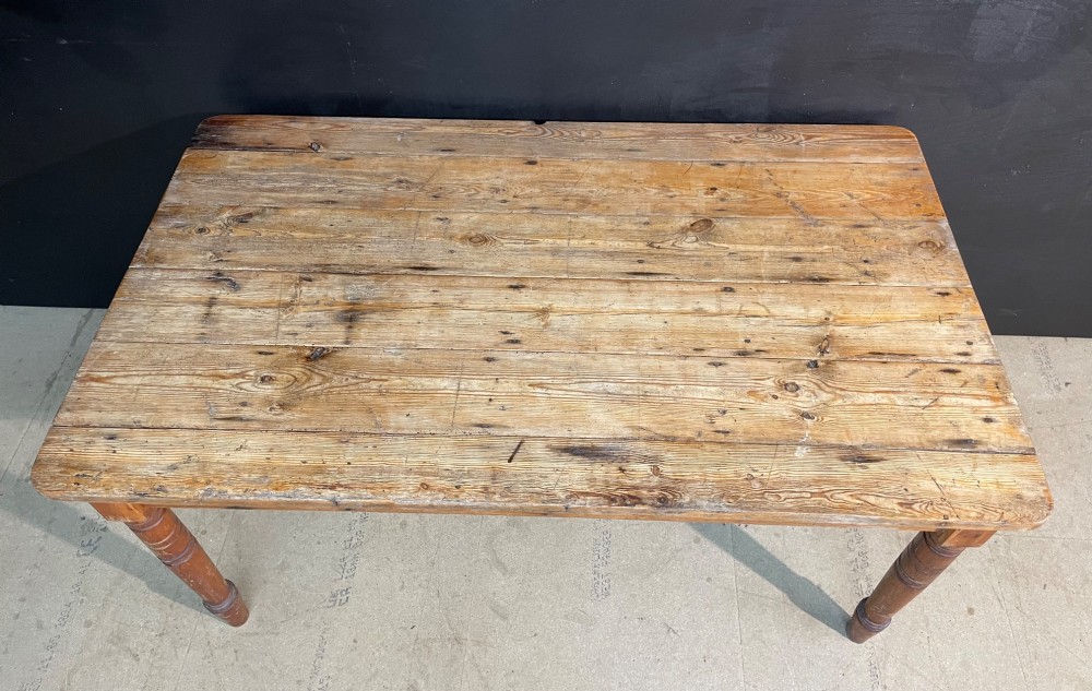 A rectangular pine farmhouse dining table with turned wooden legs and a planked top. View V