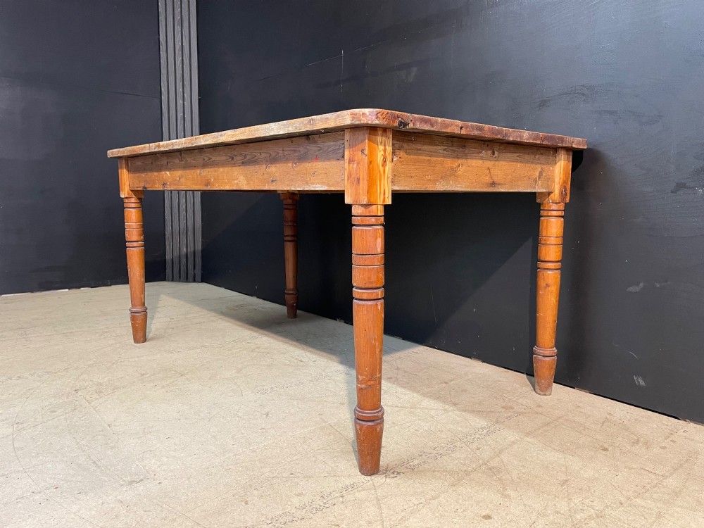 A rectangular pine farmhouse dining table with turned wooden legs and a planked top. View IX