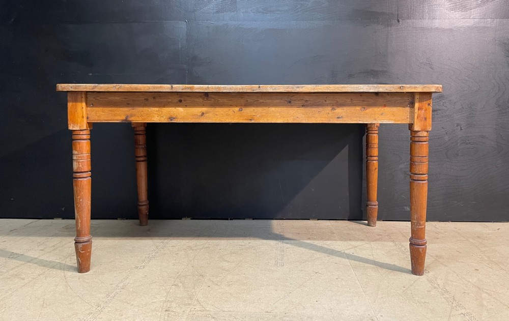 A rectangular pine farmhouse dining table with turned wooden legs and a planked top. View X