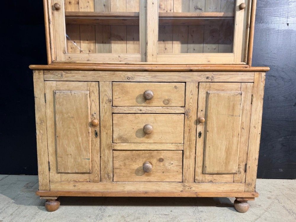 A two-tier warm pine kitchen dresser featuring an upper glazed two-door cabinet with shelves over a lower base containing three central drawers and two side cupboards. View IV
