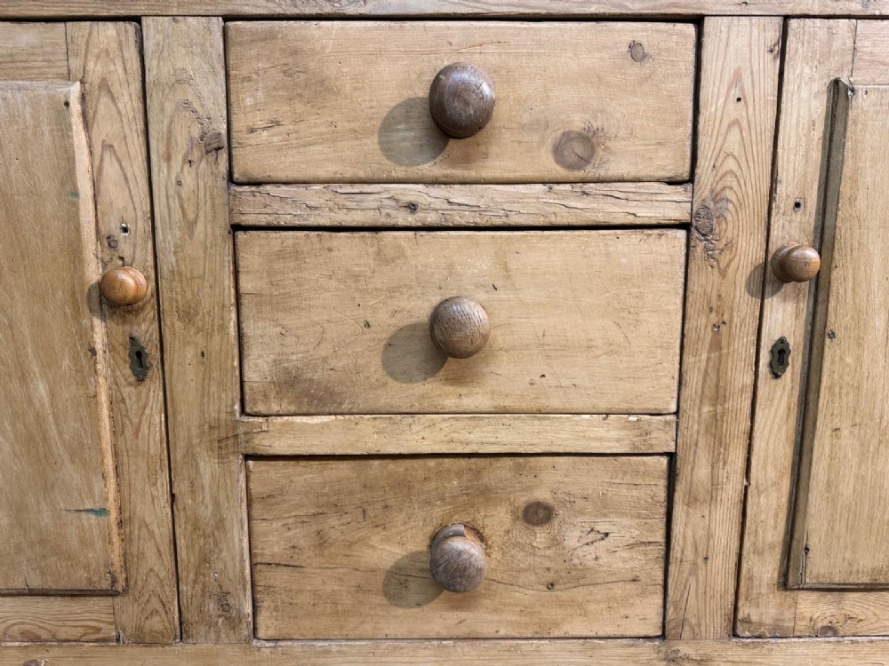 A two-tier warm pine kitchen dresser featuring an upper glazed two-door cabinet with shelves over a lower base containing three central drawers and two side cupboards. View V