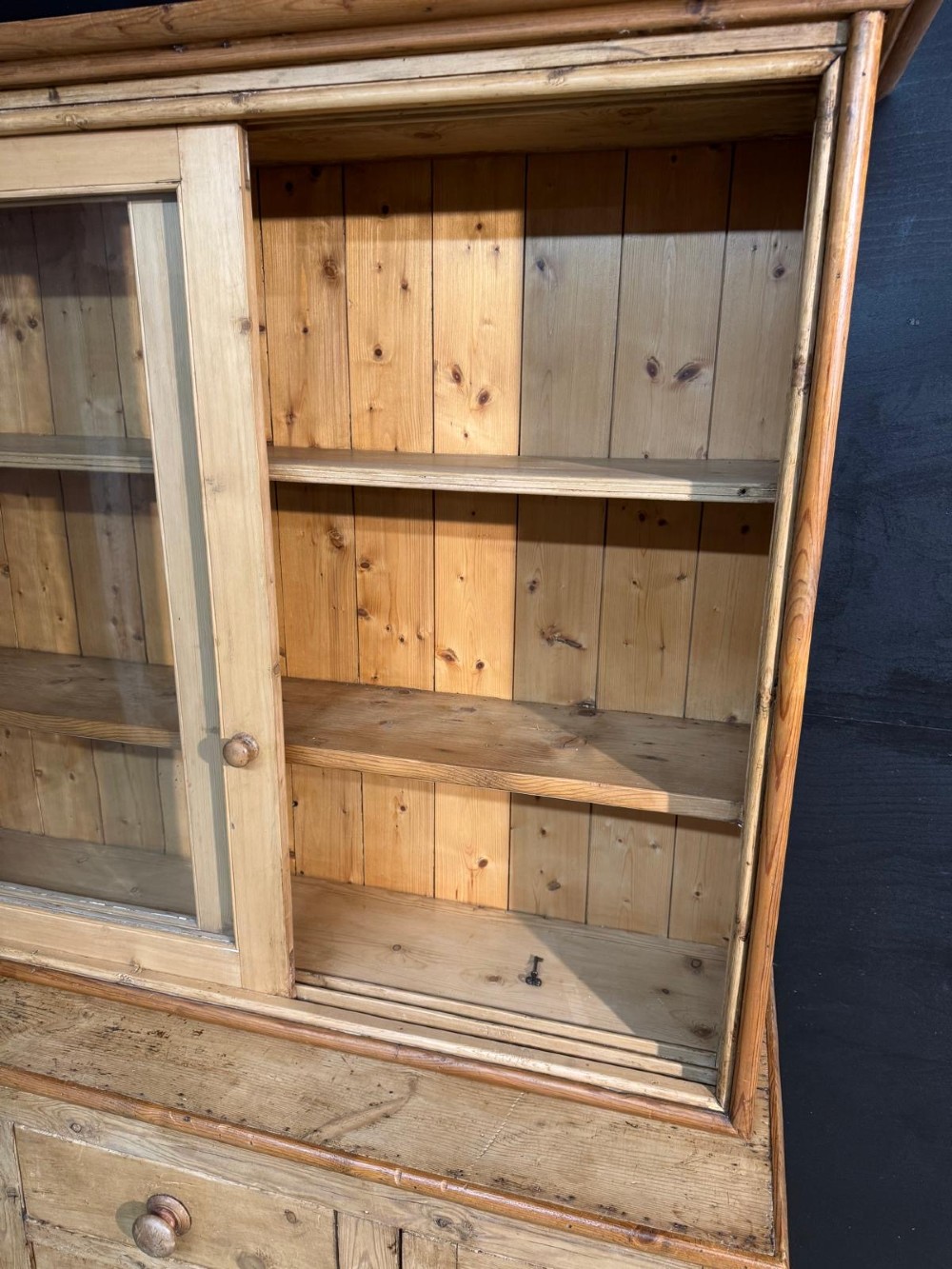 A two-tier warm pine kitchen dresser featuring an upper glazed two-door cabinet with shelves over a lower base containing three central drawers and two side cupboards. View VIII