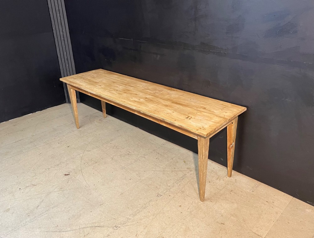 A long scrubbed pine dining table featuring a planked top surface and four tapered square legs. View II