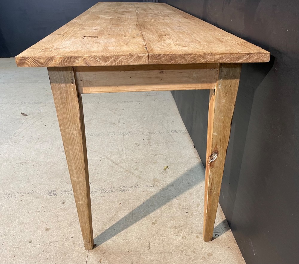A long scrubbed pine dining table featuring a planked top surface and four tapered square legs. View III