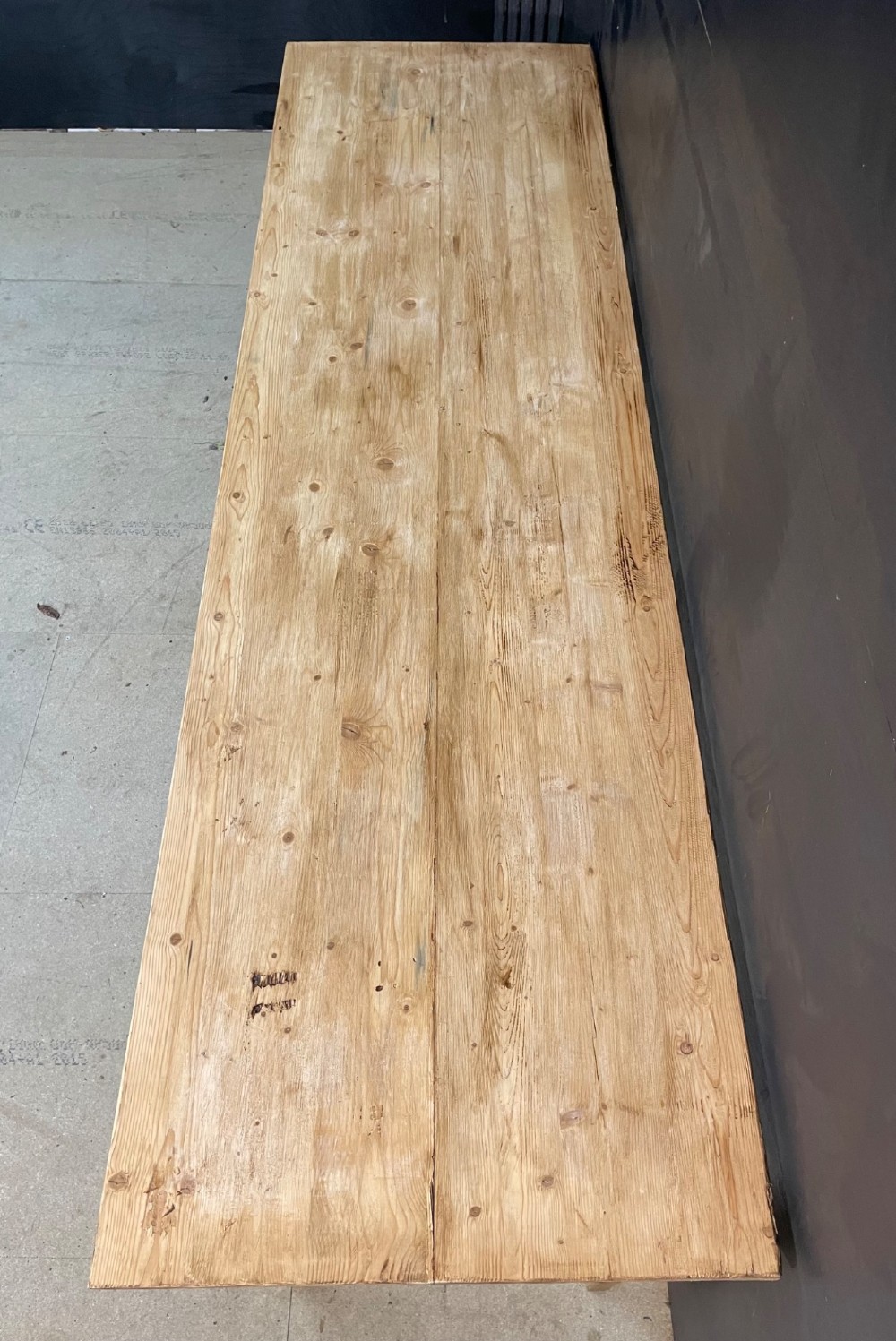 A long scrubbed pine dining table featuring a planked top surface and four tapered square legs. View V