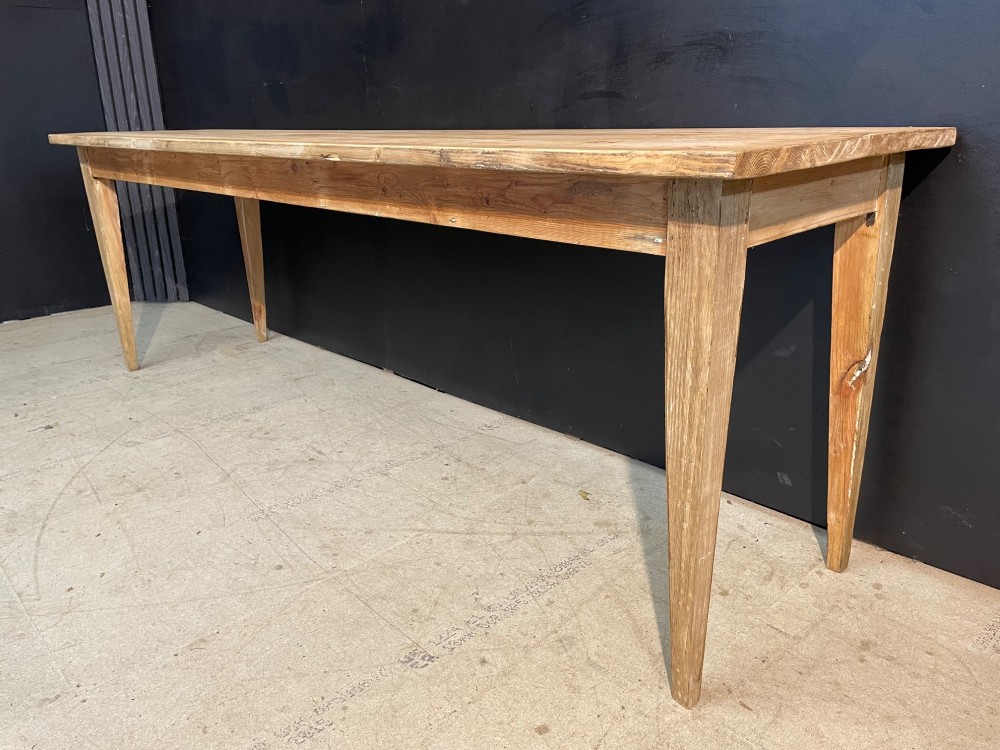 A long scrubbed pine dining table featuring a planked top surface and four tapered square legs. View VIII