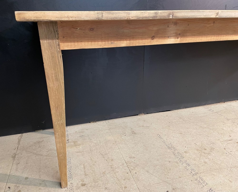 A long scrubbed pine dining table featuring a planked top surface and four tapered square legs. View IX