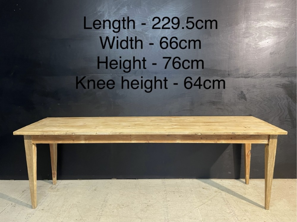 A long scrubbed pine dining table featuring a planked top surface and four tapered square legs. View X