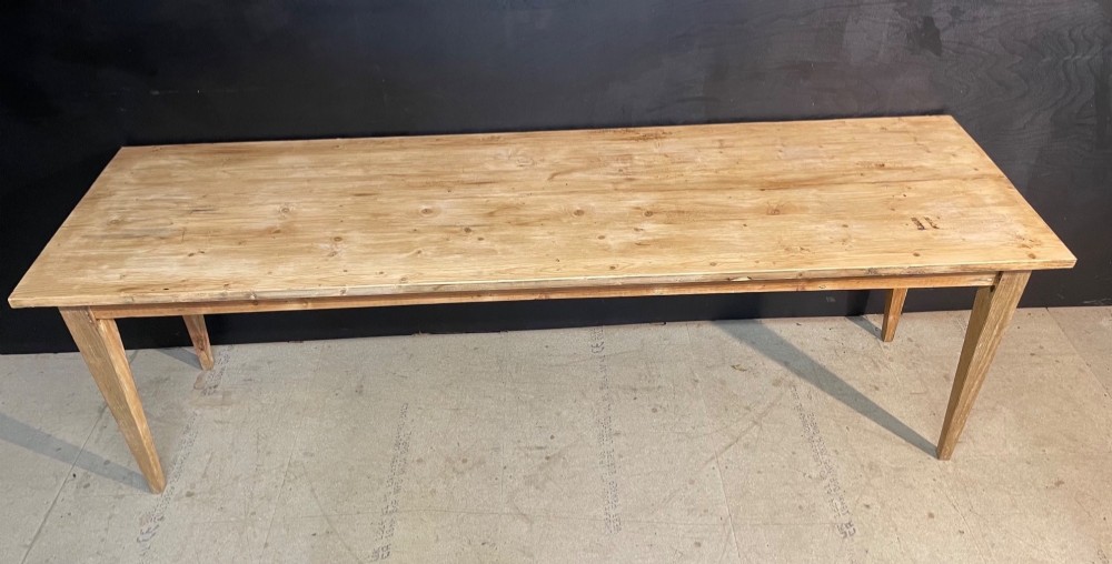 A long scrubbed pine dining table featuring a planked top surface and four tapered square legs. View VI
