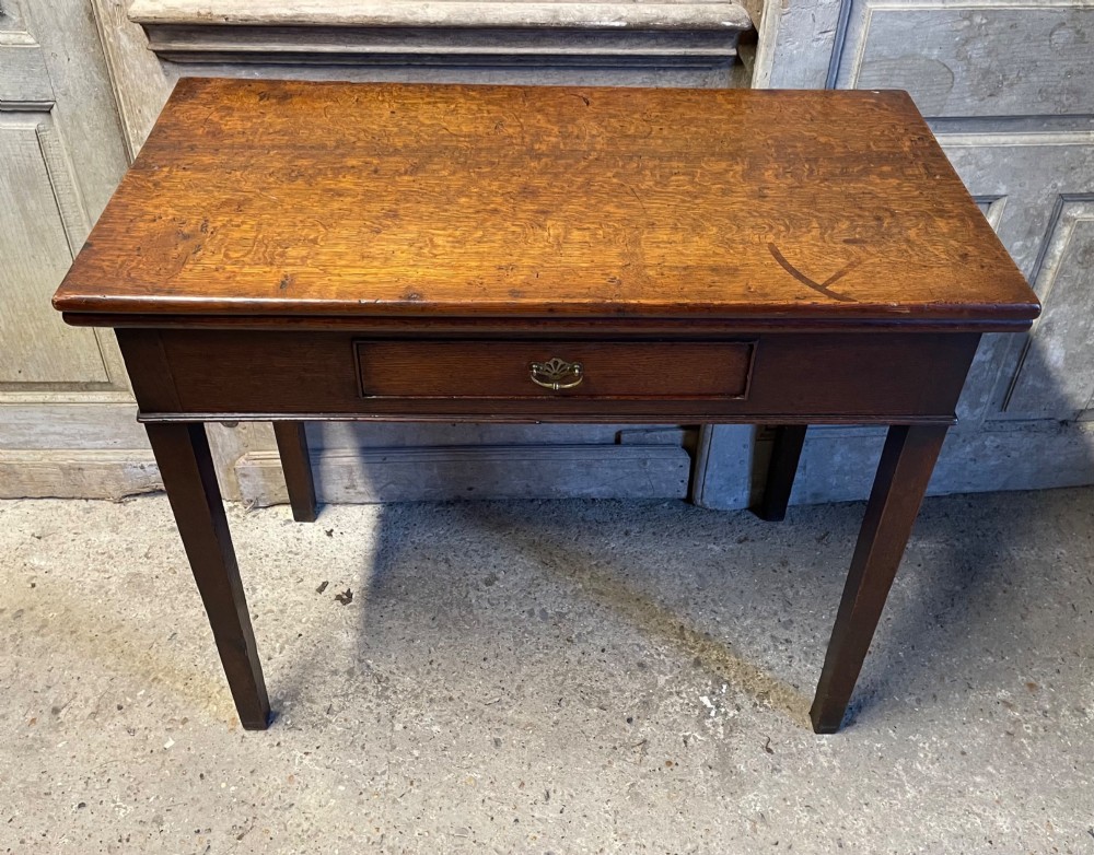 A Georgian oak fold-over tea table featuring a single central frieze drawer with a brass drop handle and straight tapered legs. View II