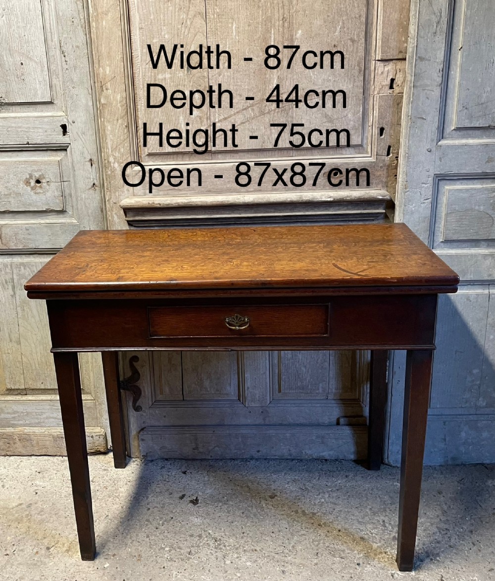 A Georgian oak fold-over tea table featuring a single central frieze drawer with a brass drop handle and straight tapered legs. View VIII