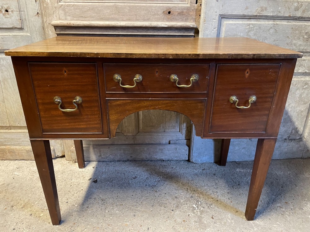 A 19th-century mahogany lowboy with three drawers, brass swan-neck handles, an arched lower apron, and square tapered legs. View IV