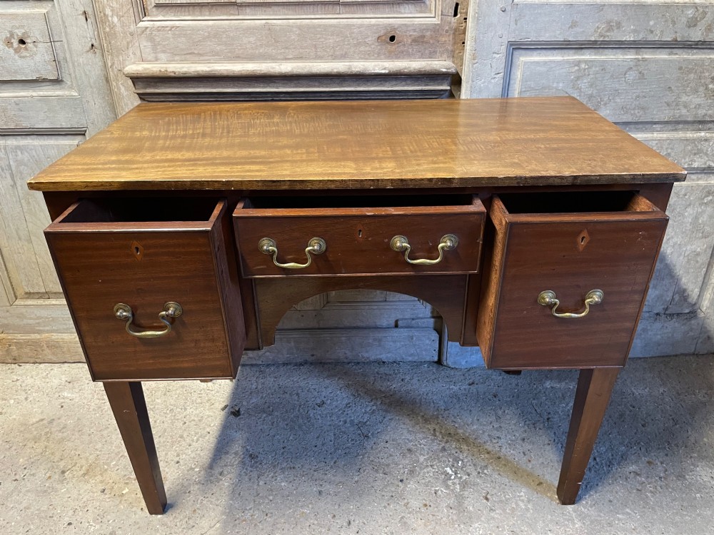A 19th-century mahogany lowboy with three drawers, brass swan-neck handles, an arched lower apron, and square tapered legs. View V