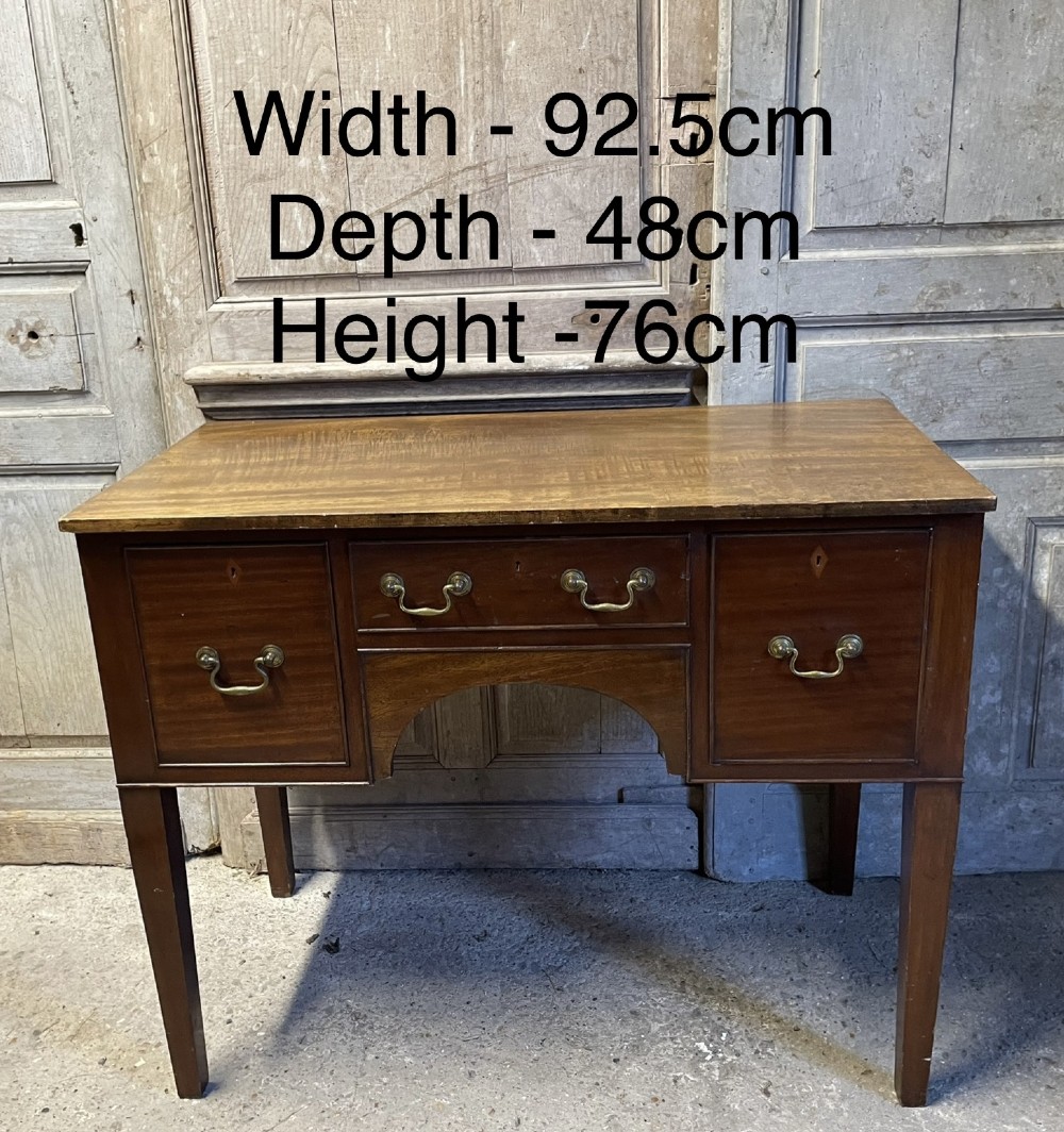 A 19th-century mahogany lowboy with three drawers, brass swan-neck handles, an arched lower apron, and square tapered legs. View VI