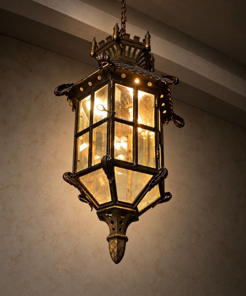 fig 1. A large Continental Gothic Revival bronze hanging lantern featuring a castellated crown roof with turrets, scale detailing, and glass panels.