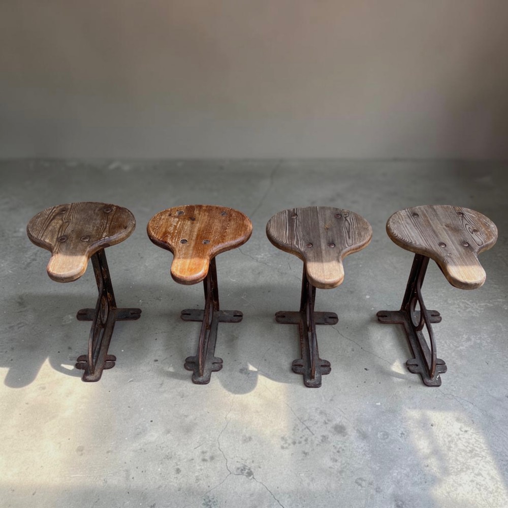 A set of four industrial machinist stools with sculpted pitch pine seats and dark cast iron cantilever bases. View V