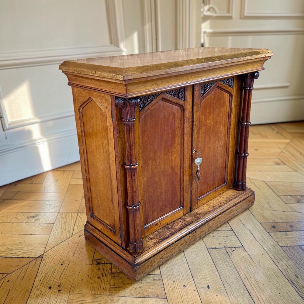 A William IV Gothic Revival oak side cabinet featuring twin pointed-arch panelled doors flanked by turned columns.