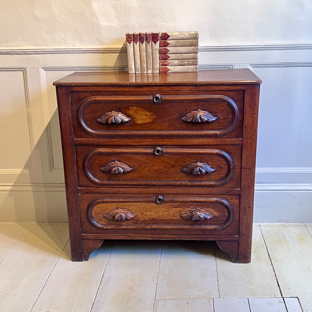 A late nineteenth-century American oak chest featuring three drawers with oval moulding and carved wooden foliate handles.