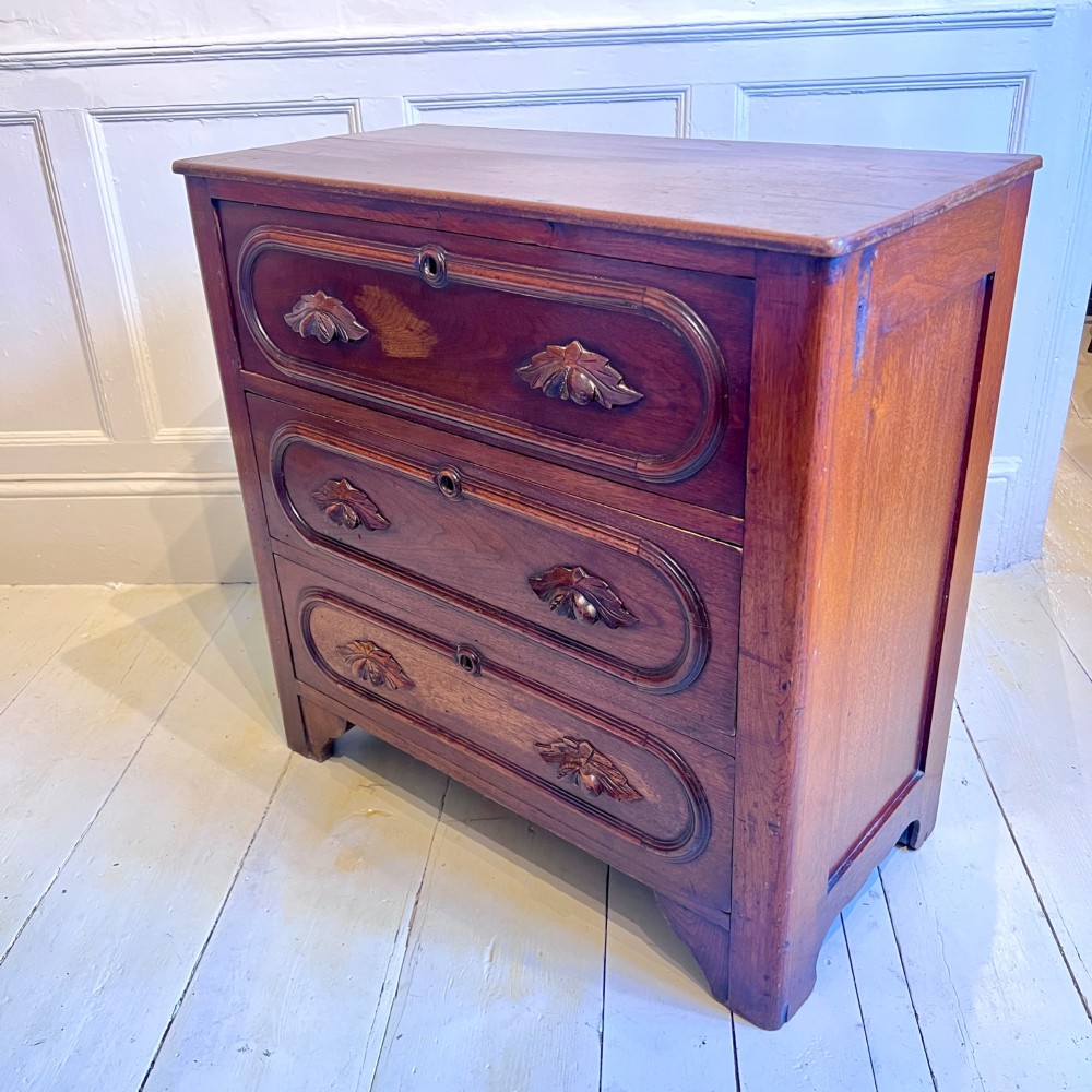 A late nineteenth-century American oak chest featuring three drawers with oval moulding and carved wooden foliate handles. View II