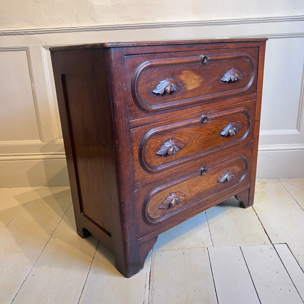 A late nineteenth-century American oak chest featuring three drawers with oval moulding and carved wooden foliate handles. View IV