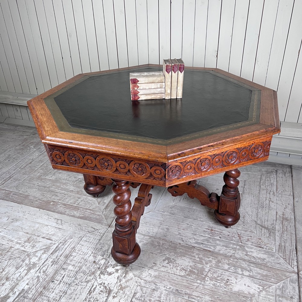 An octagonal Victorian oak centre table featuring a carved rosette frieze, barley twist legs, a central finial stretcher, and an inset leather top. View II