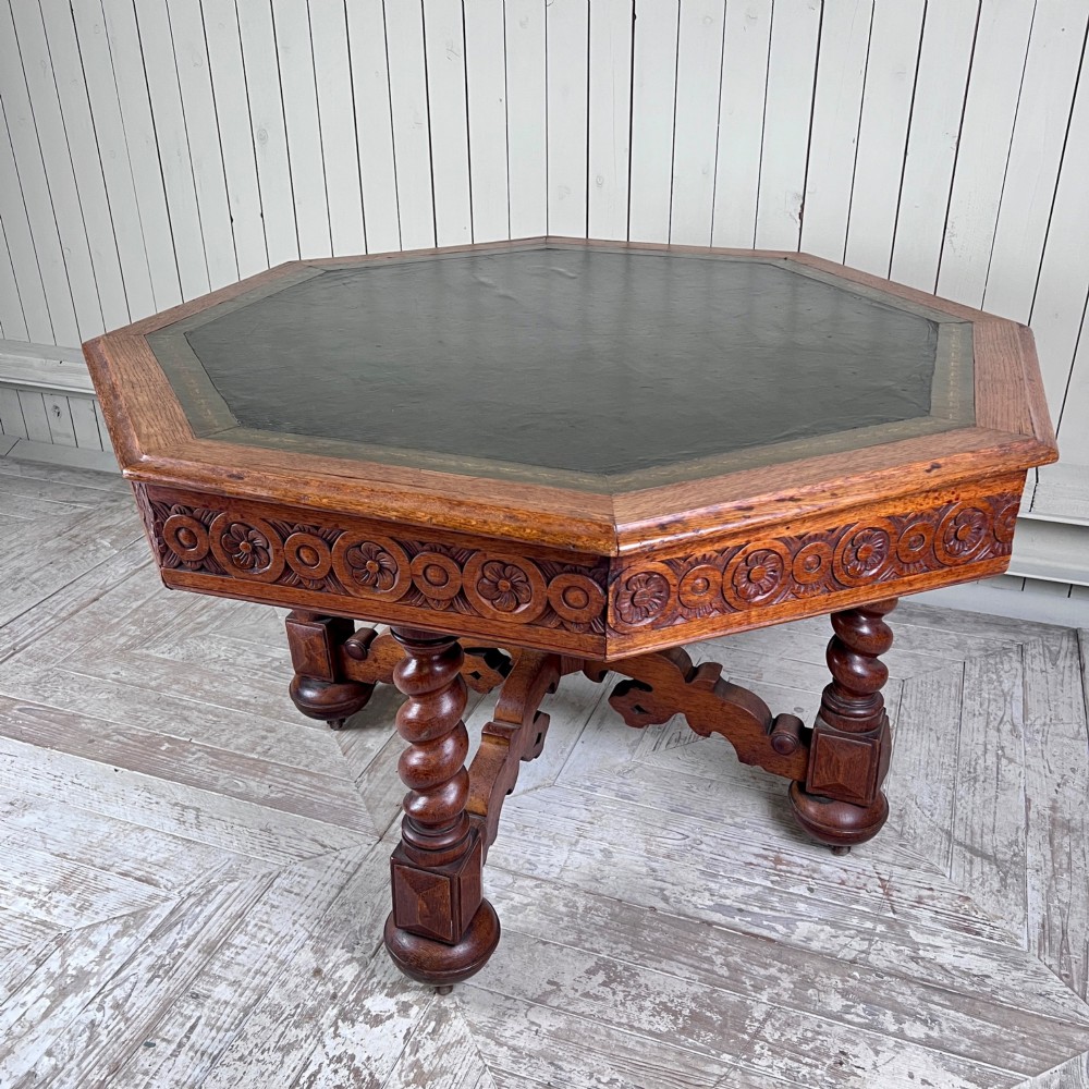 An octagonal Victorian oak centre table featuring a carved rosette frieze, barley twist legs, a central finial stretcher, and an inset leather top. View III