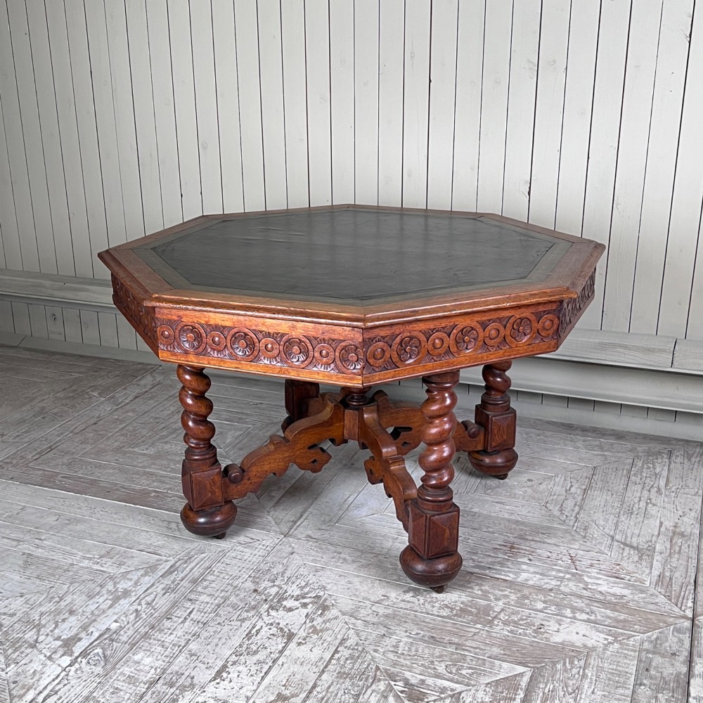 An octagonal Victorian oak centre table featuring a carved rosette frieze, barley twist legs, a central finial stretcher, and an inset leather top. View IV