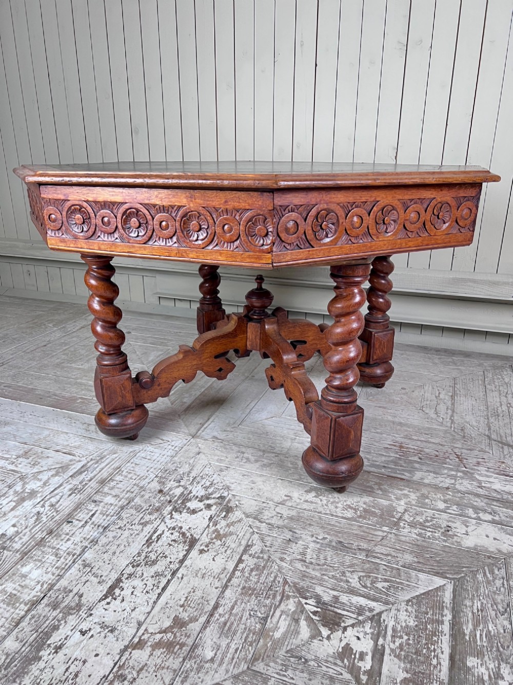 An octagonal Victorian oak centre table featuring a carved rosette frieze, barley twist legs, a central finial stretcher, and an inset leather top. View V