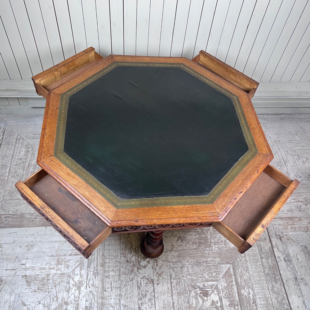 An octagonal Victorian oak centre table featuring a carved rosette frieze, barley twist legs, a central finial stretcher, and an inset leather top. View VI