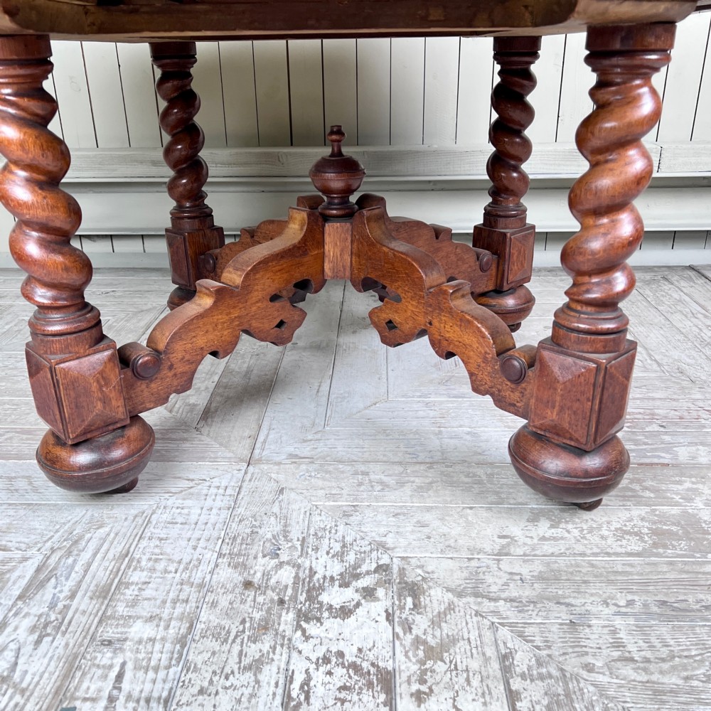 An octagonal Victorian oak centre table featuring a carved rosette frieze, barley twist legs, a central finial stretcher, and an inset leather top. View VII