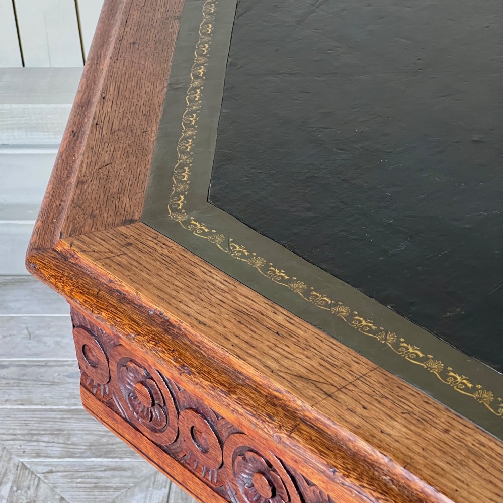 An octagonal Victorian oak centre table featuring a carved rosette frieze, barley twist legs, a central finial stretcher, and an inset leather top. View VIII