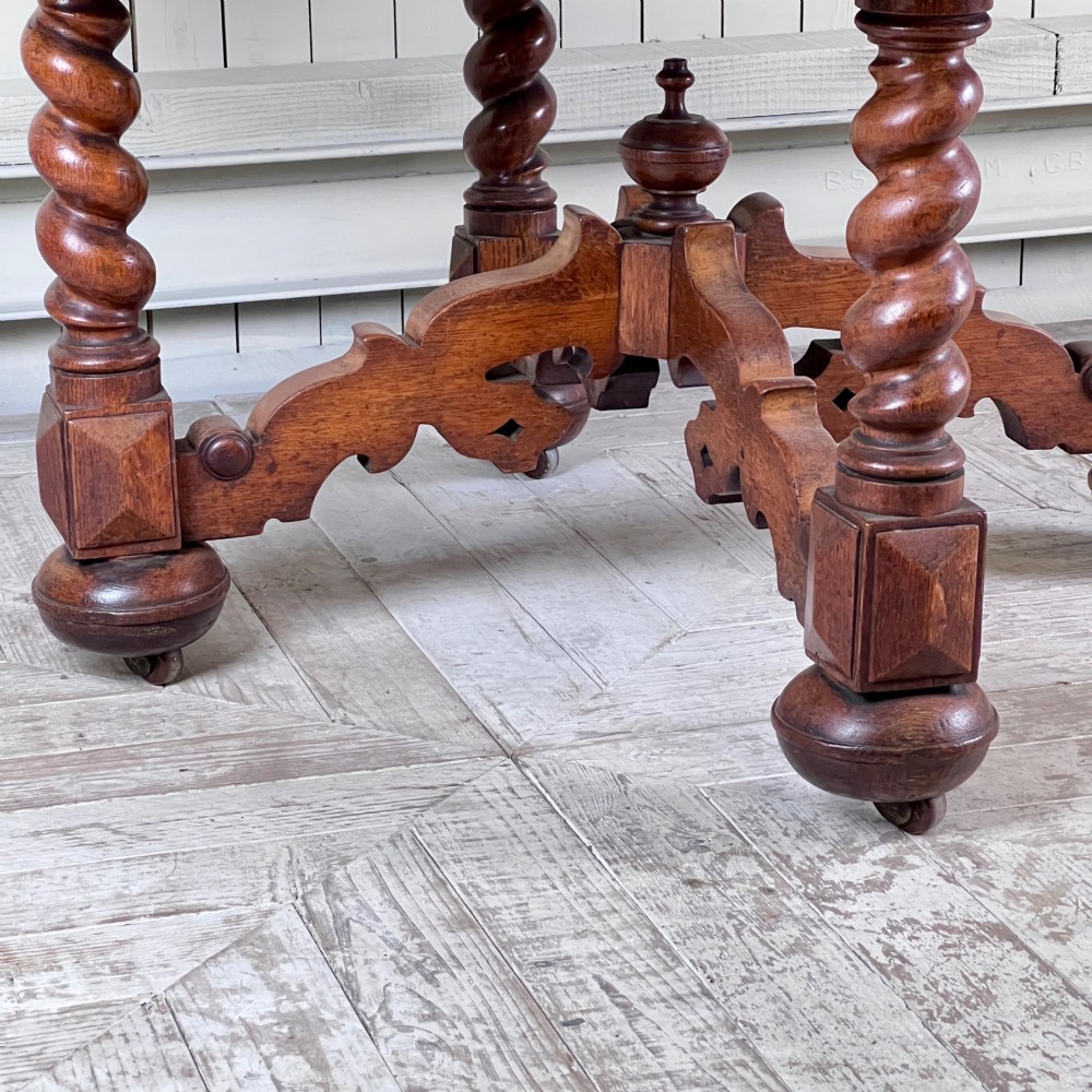 An octagonal Victorian oak centre table featuring a carved rosette frieze, barley twist legs, a central finial stretcher, and an inset leather top. View X