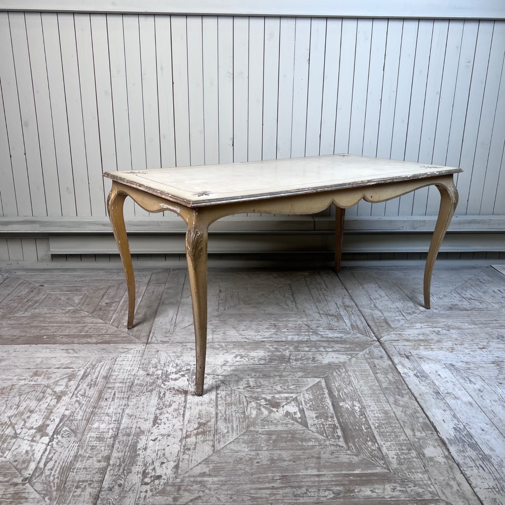 A rectangular French Louis XV Revival dining table featuring a cream painted finish, gold leaf accents, curved cabriole legs, and a scalloped apron. View II