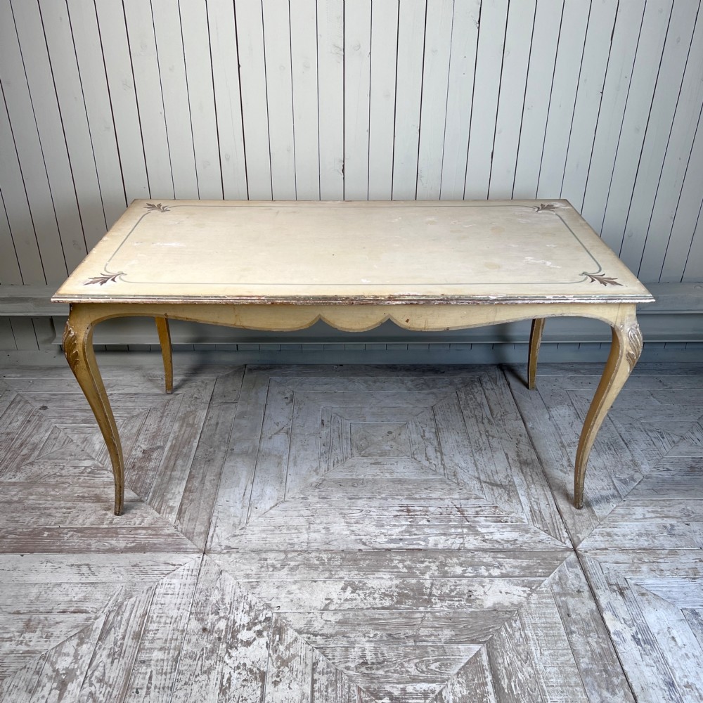 A rectangular French Louis XV Revival dining table featuring a cream painted finish, gold leaf accents, curved cabriole legs, and a scalloped apron. View V