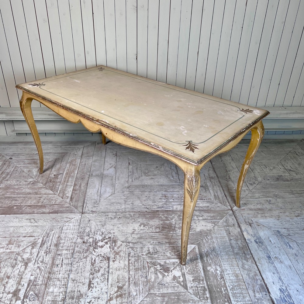 A rectangular French Louis XV Revival dining table featuring a cream painted finish, gold leaf accents, curved cabriole legs, and a scalloped apron. View IX