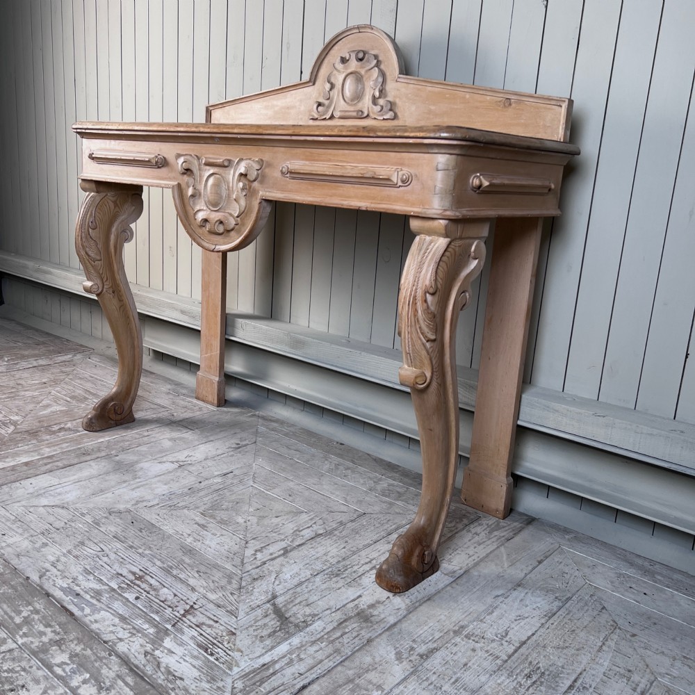 A Victorian carved pine console table featuring front cabriole legs, a central relief cartouche, and a shaped gallery backrest. View IV