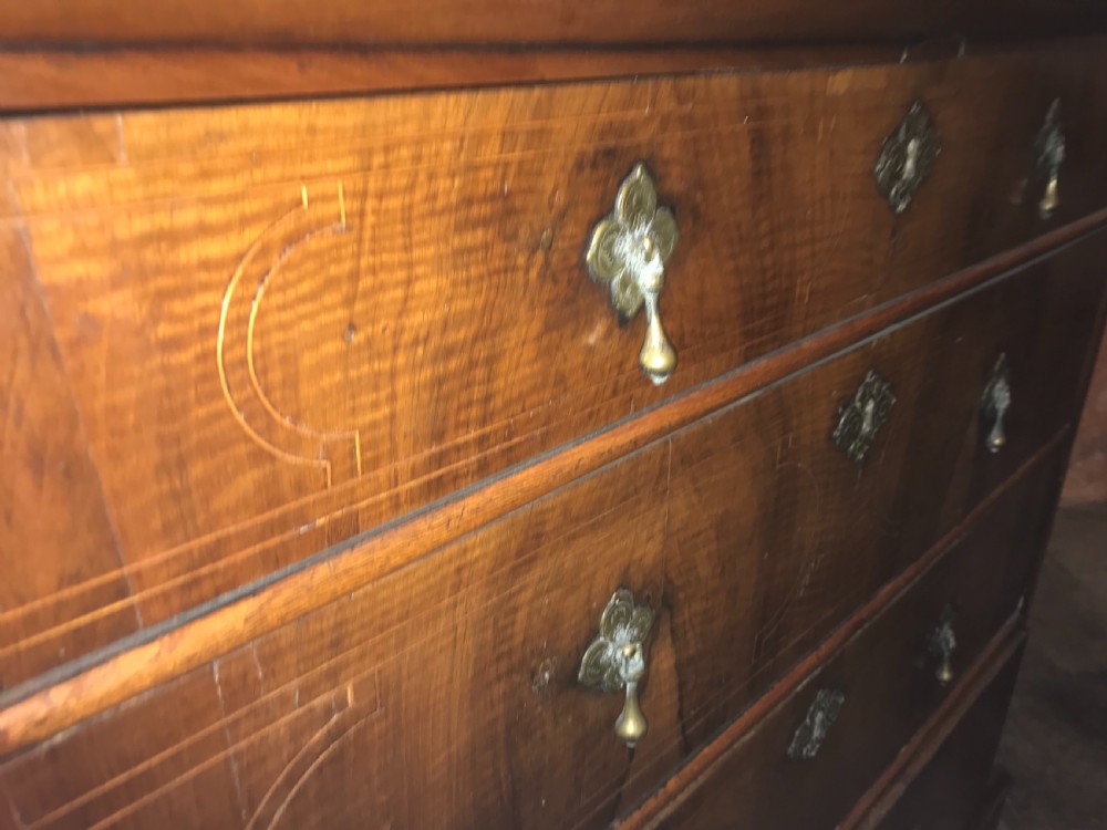 An early eighteenth-century walnut chest of drawers featuring four graduated drawers with geometric stringing inlay, brass teardrop handles, and bracket feet. View III