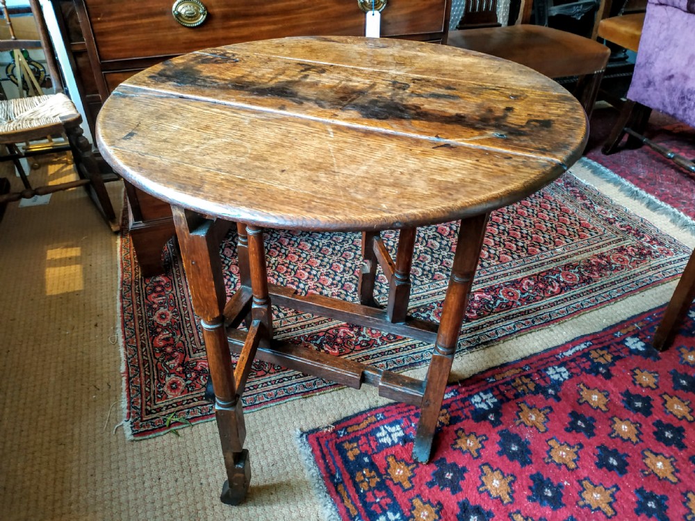A 19th-century round oak gateleg occasional table featuring a drop-leaf top, turned legs, and a lower stretcher frame.