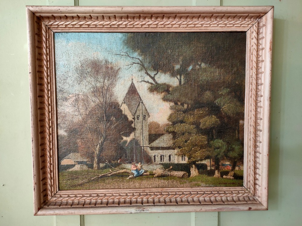A framed oil painting on canvas depicting a traditional English rural scene with a church tower, mature trees, and figures resting near a fallen log.