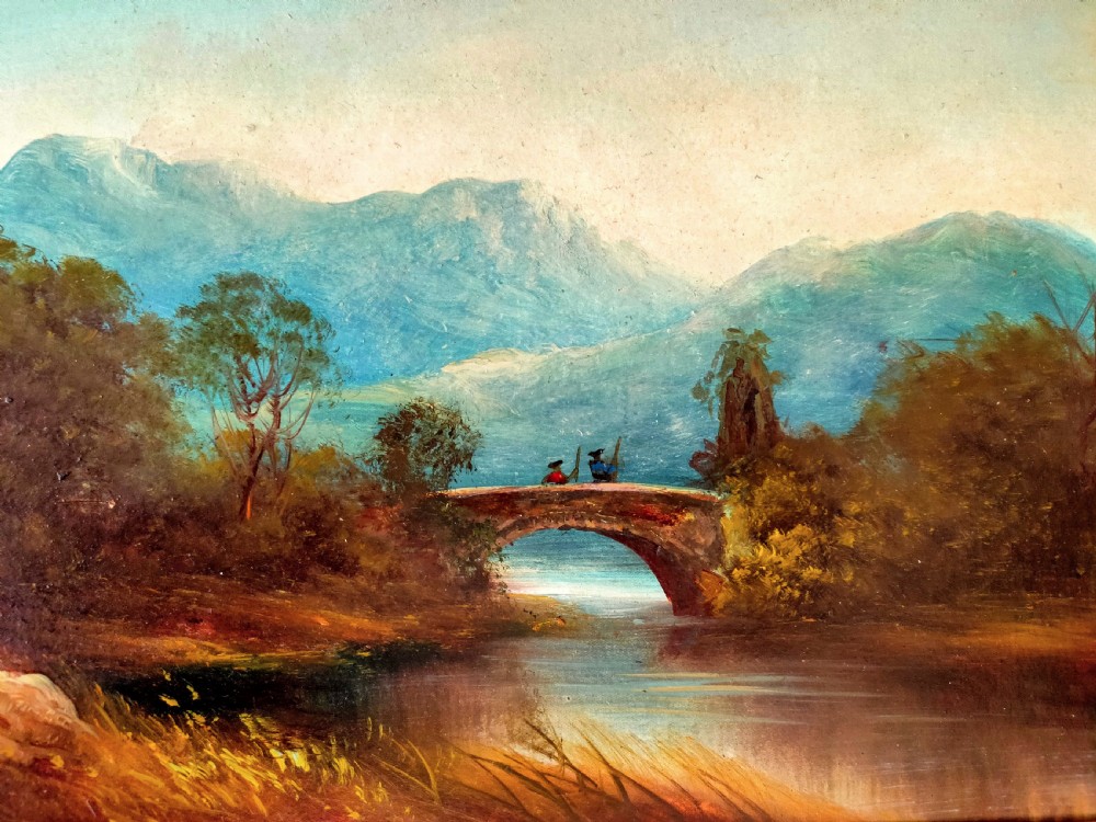 An antique landscape oil painting portraying two figures standing on a stone arch bridge over a river with blue mountains in the background, set inside an ornate gold frame. View IV