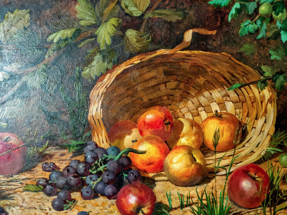 A framed oil painting featuring a tilted wicker basket with apples and purple grapes resting on ground surrounded by foliage. View II