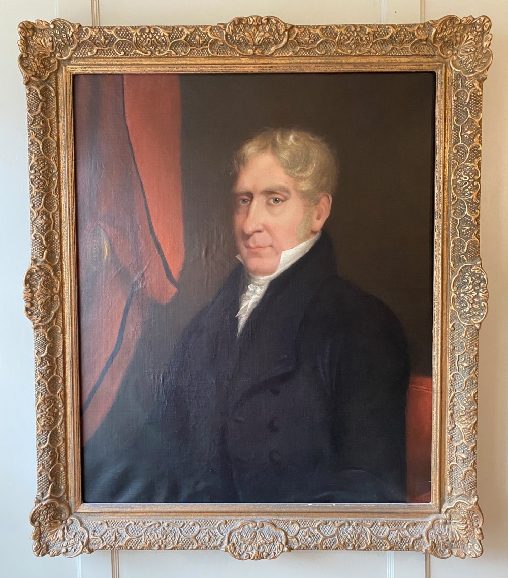 A 19th-century oil painting depicting a fair-haired gentleman in a dark frock coat and white cravat, set within an ornate gilded frame.