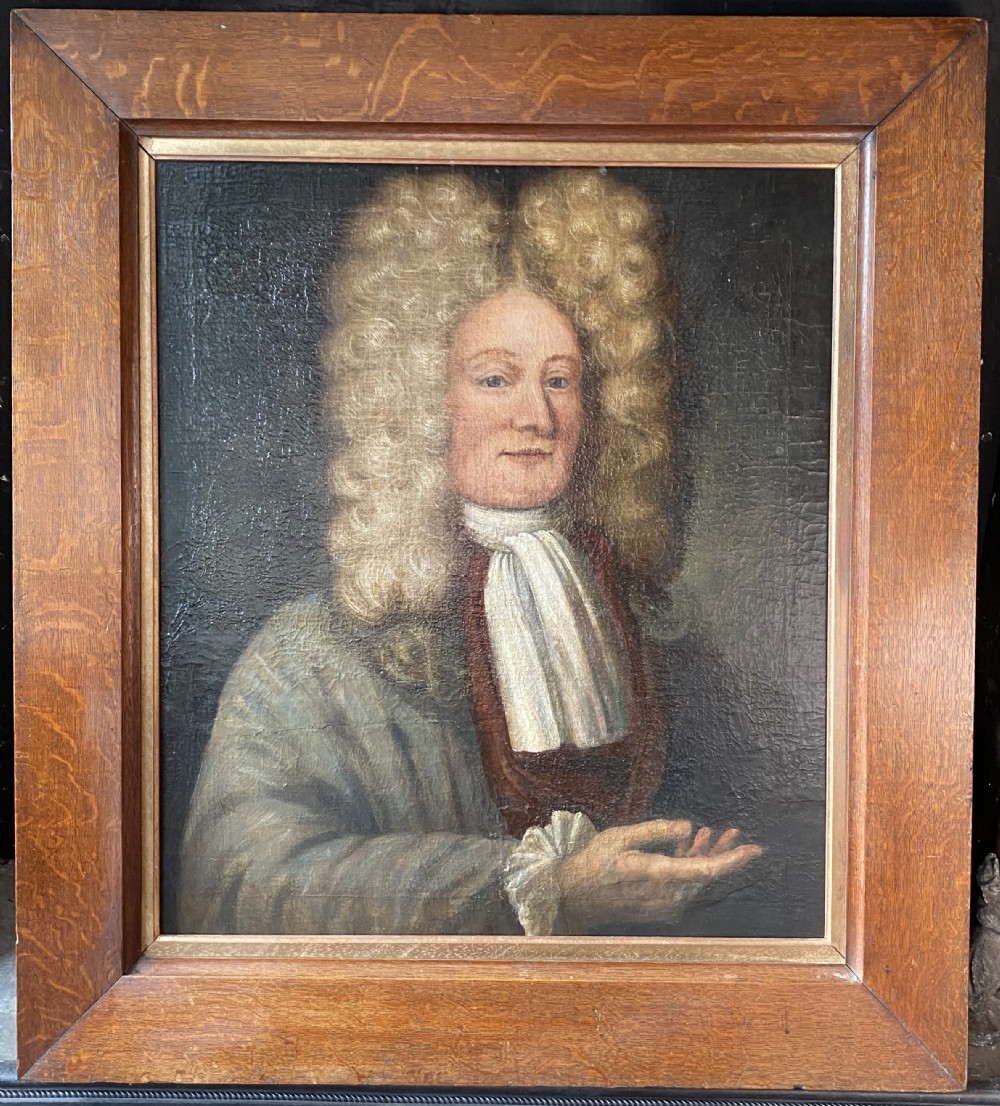 An 18th-century oil painting depicting a gentleman wearing a powdered wig and white cravat, framed within a wide oak wood border.