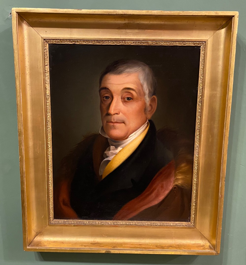 A 19th-century oil portrait depicting a gentleman with grey hair, a yellow collar, and a fur-trimmed coat, framed within a molded giltwood frame.