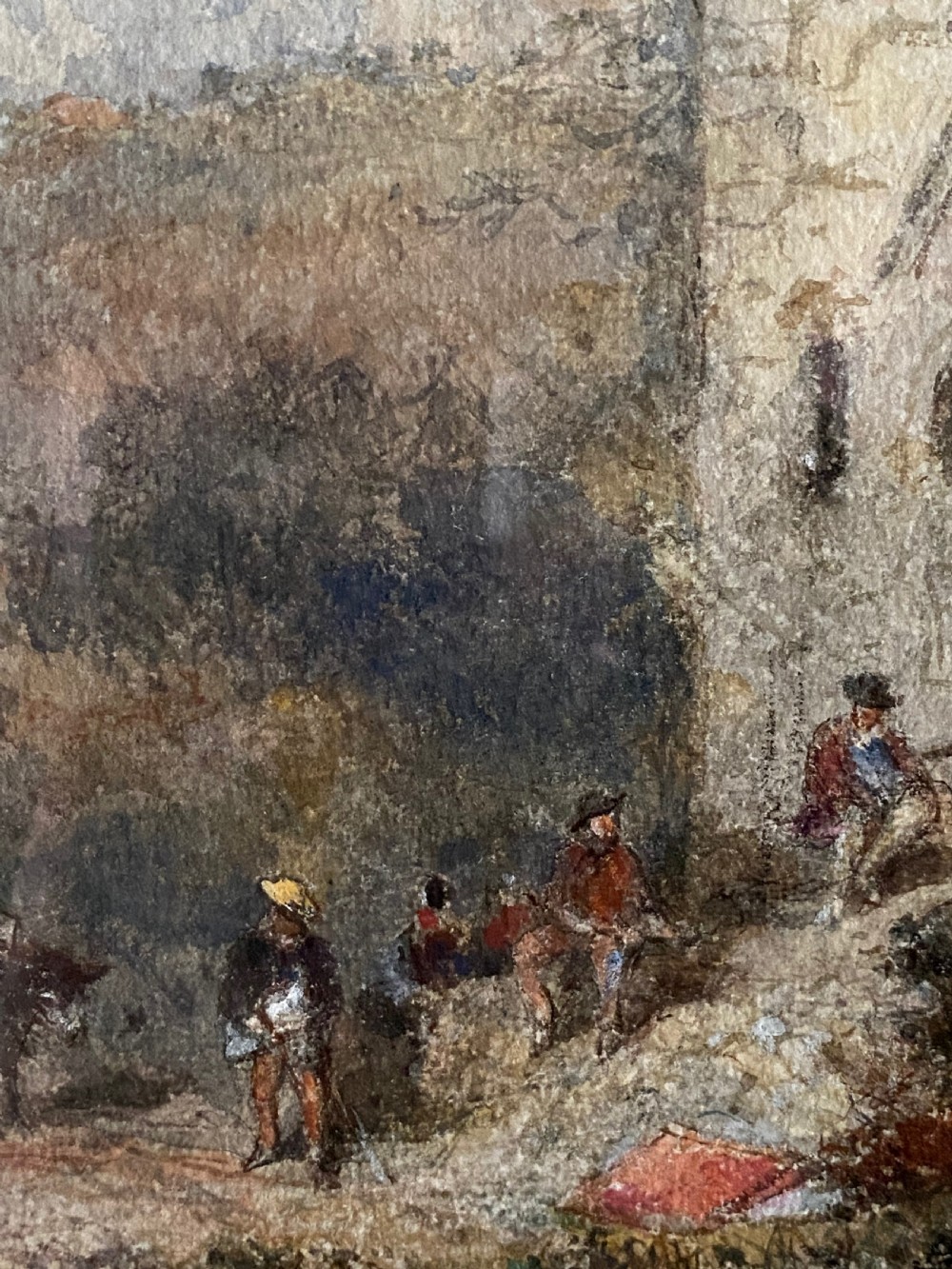 An early 20th-century watercolour painting depicting figures near a rustic stone building in a hilly landscape, presented in a gilded frame. View IV