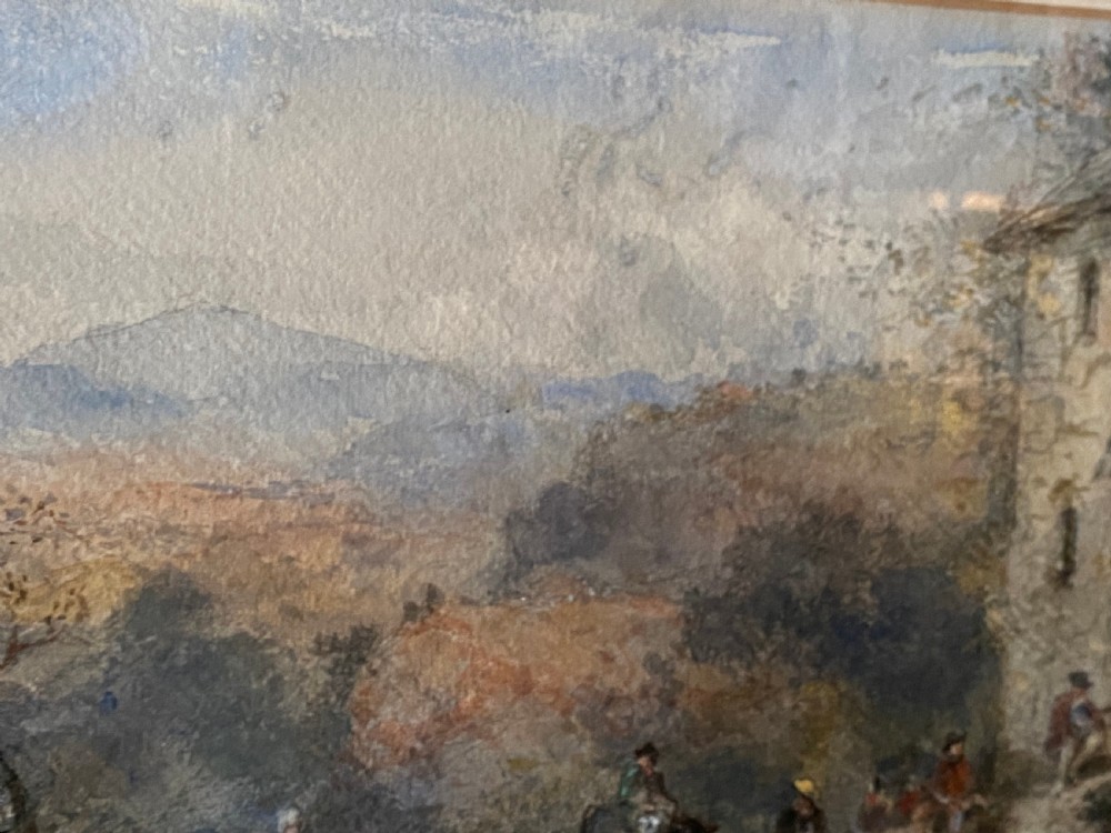 An early 20th-century watercolour painting depicting figures near a rustic stone building in a hilly landscape, presented in a gilded frame. View V