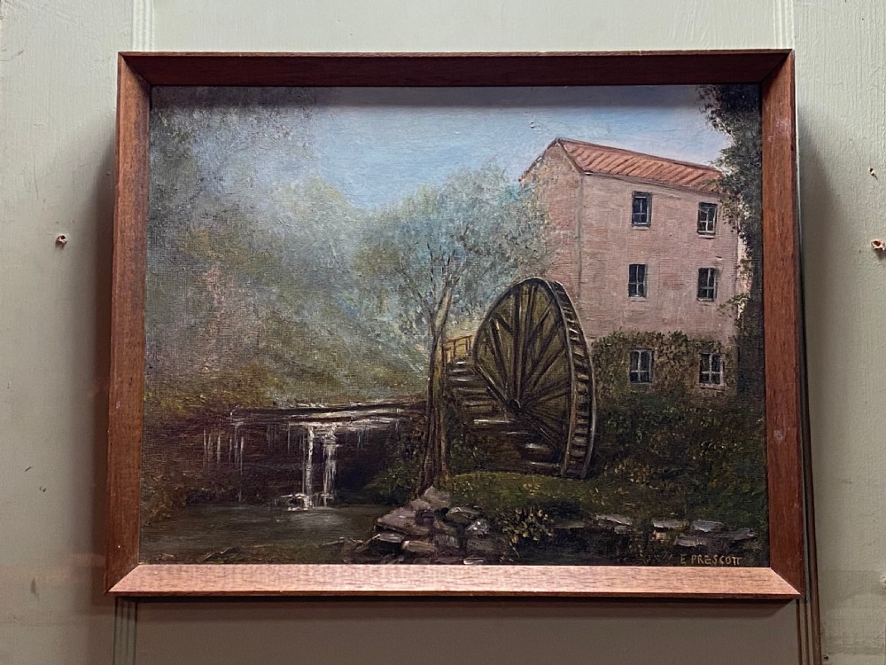 A rectangular framed oil painting illustrating a stone water mill beside a stream and waterfall, signed by E. Prescott in the bottom right corner.