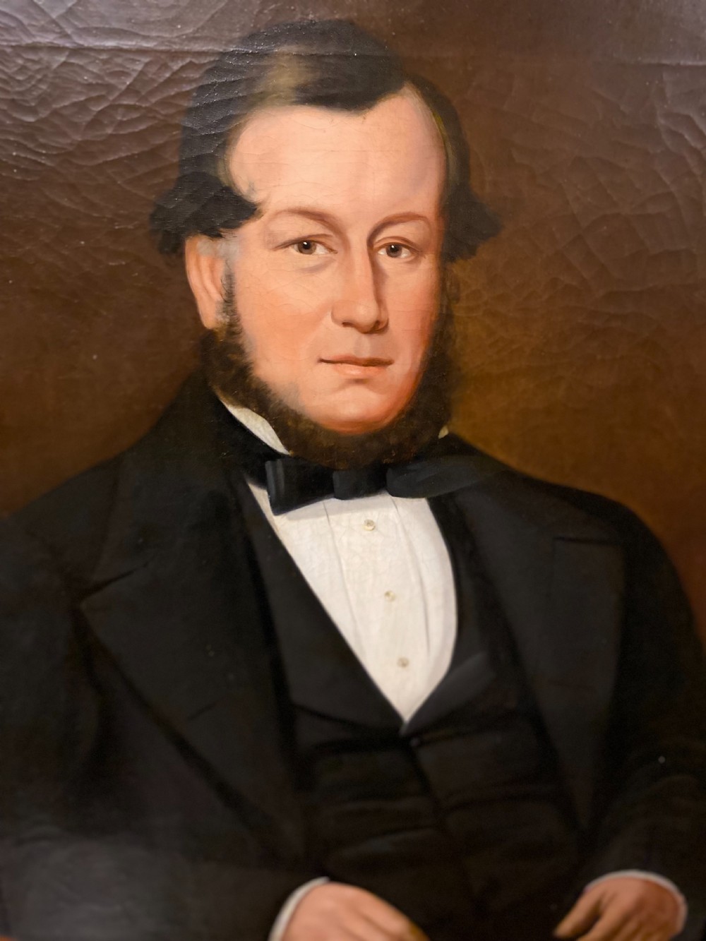 A 19th-century oil painting on canvas depicting a seated gentleman in black formal wear, set within an ornate gilded frame. View II